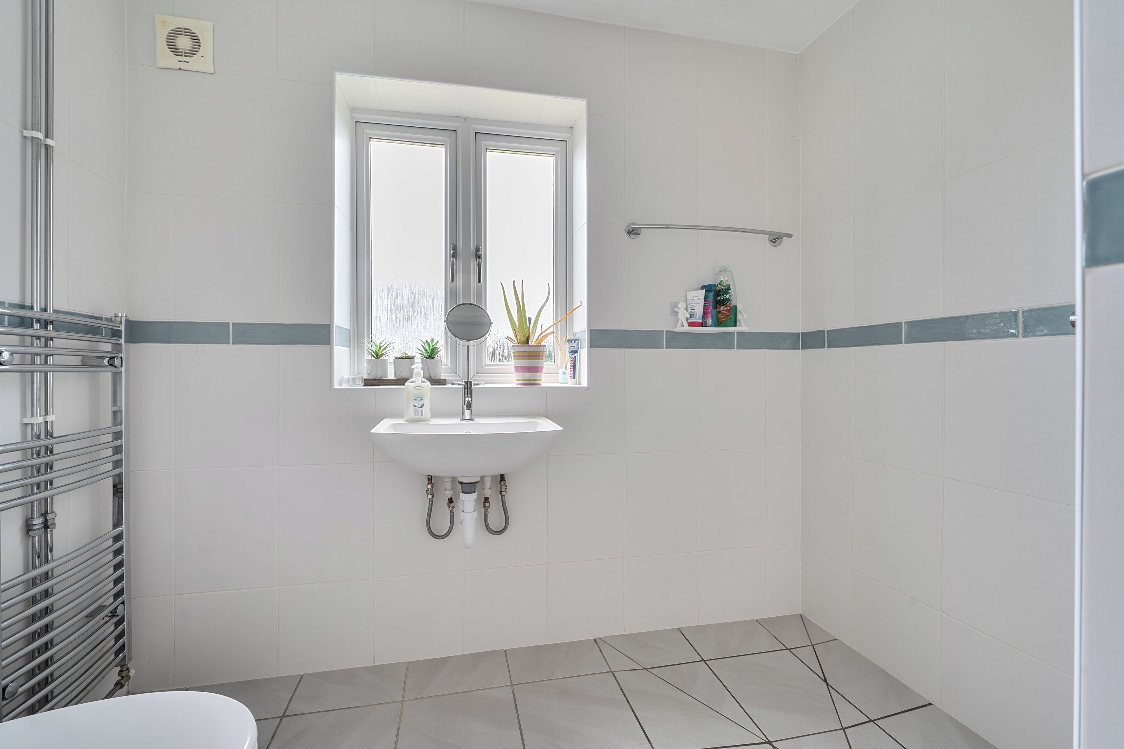 A bathroom with a white sink, a window, and a shower area.