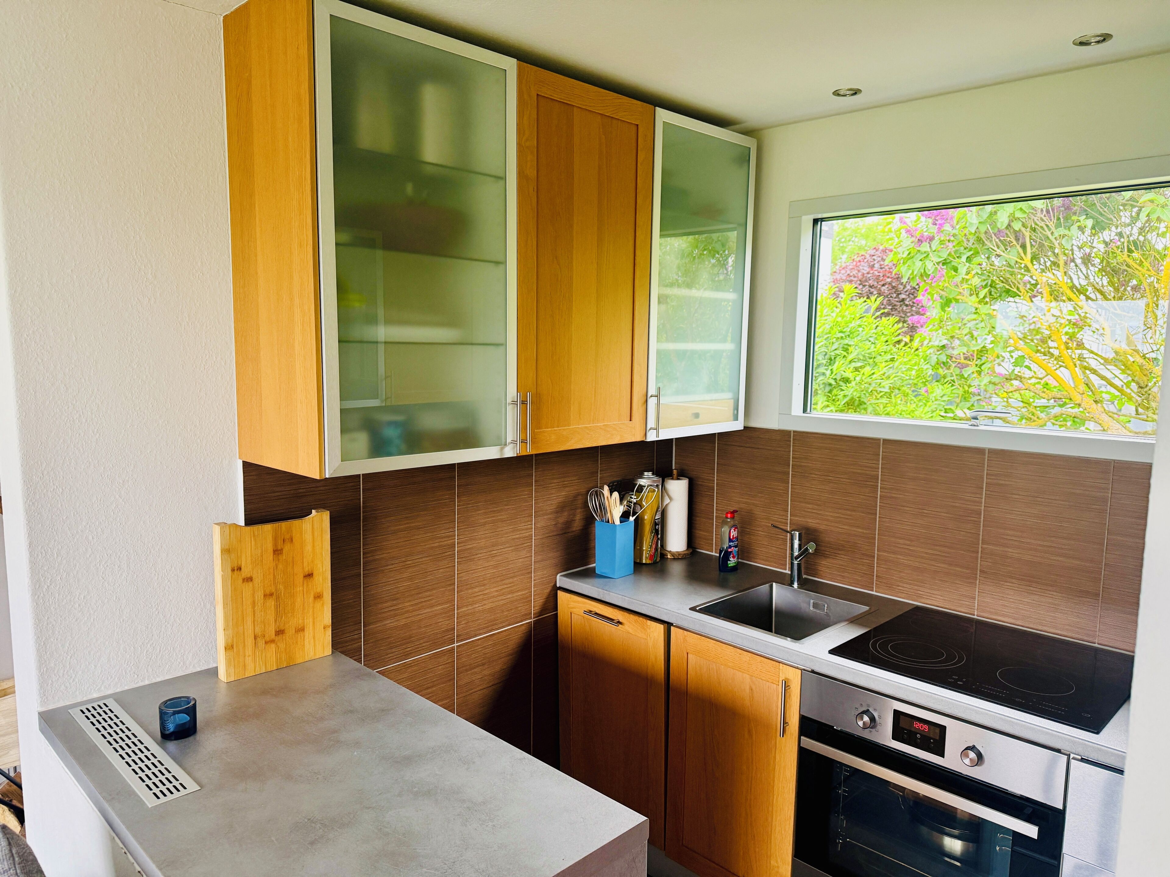 Une cuisine moderne avec des meubles en bois, un évier en acier inoxydable et un four.