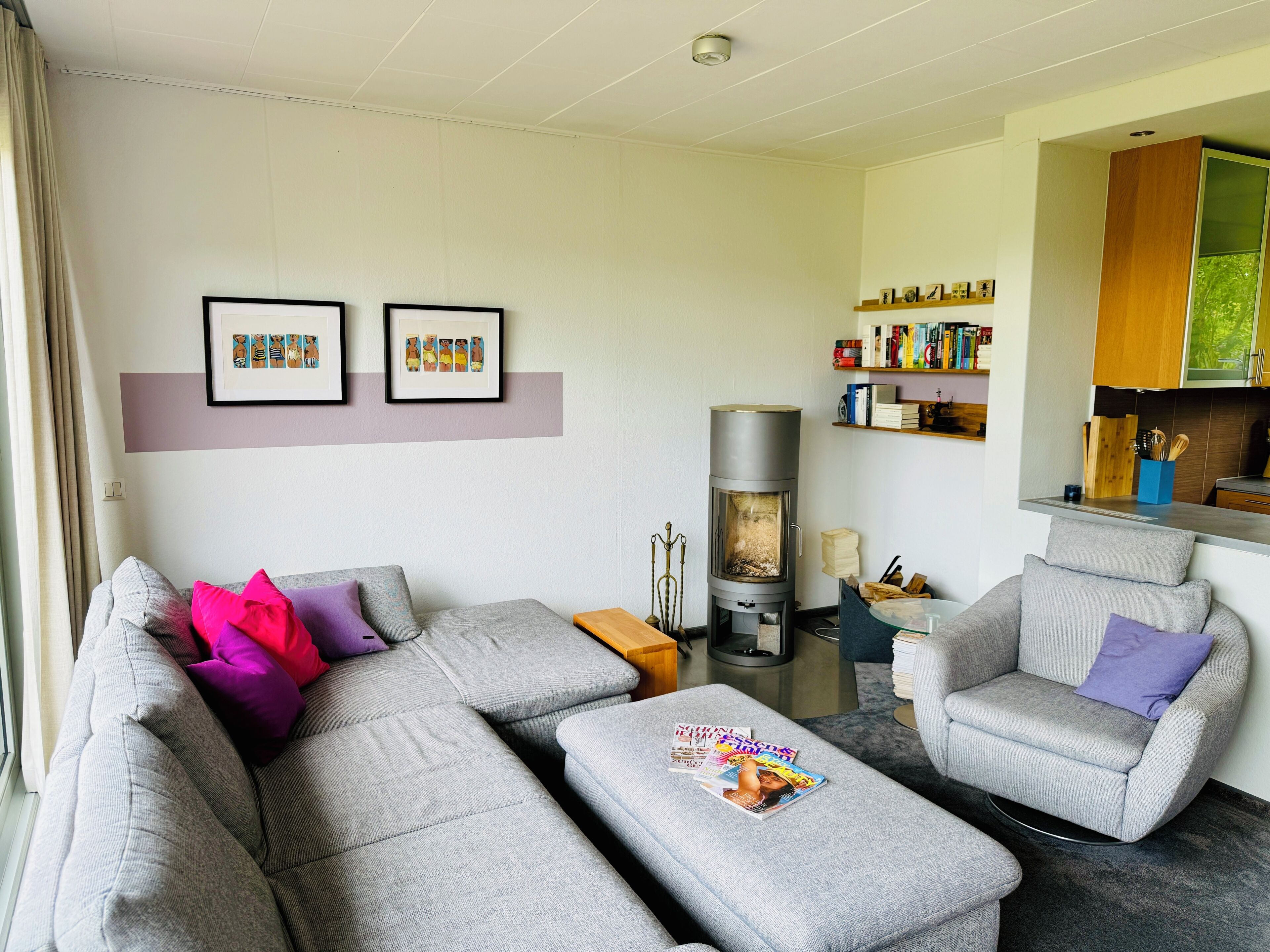 A living room with a sofa, ottoman, and armchair, a fireplace, and a bookshelf.