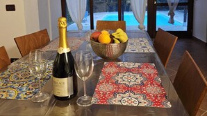 Un tavolo da pranzo con una bottiglia di champagne, bicchieri da vino e una ciotola di frutta.