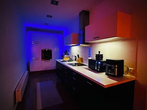 Una cocina moderna con horno empotrado, microondas y cafetera.