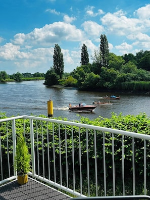 Un río con barcos, vegetación y una barandilla.