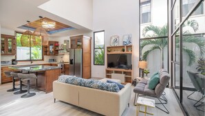 Eine moderne Küche mit Kochinsel, Barhocker, einer Couch und einem Fernseher.