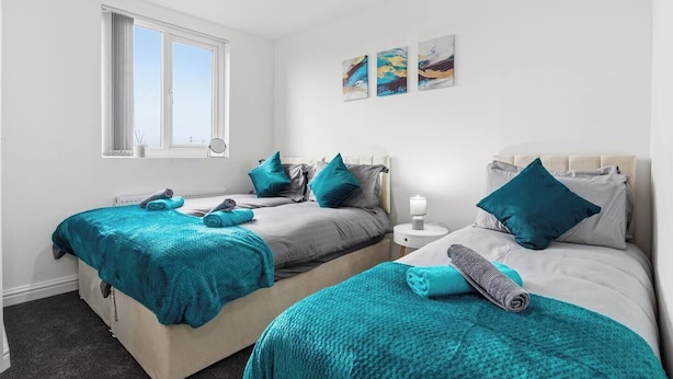 A bedroom with two beds, a window, and artwork on the wall. - Central | FREE parking | Connections to Manchester (Cheshire)