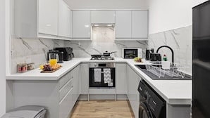 A compact kitchen with white cabinets, a microwave, a coffee maker, and a dishwasher. - Central | FREE parking | Connections to Manchester (Cheshire)