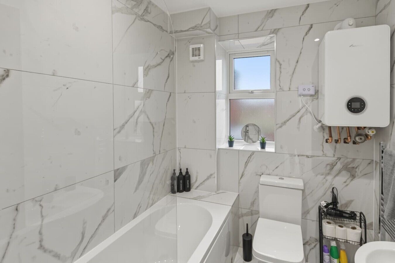 Een badkamer met een bad, toilet en een raam met uitzicht.