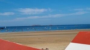 Ein Strand mit Booten, einem Leuchtturm und einer roten und weißen Struktur im Vordergrund.