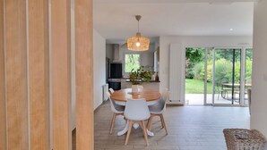 Moderni keittiö, jossa on ruokailutila, suuret ikkunat ja näkymä ulos.