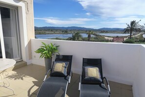 A balcony with two lounge chairs, a potted plant, and a view of a river and mountains. - Duplex 40m2 T3 large south-facing terrace 2bed, (Hyères)