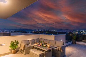 Eine Dachterrasse mit Essbereich, Sitzgelegenheiten und Blick auf die Stadt.