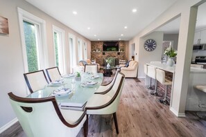 A dining area with a glass table, chairs, and a kitchen in the background.
