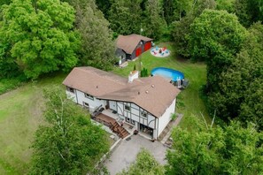 A two-story house with a large deck, a swimming pool, and a fenced yard.