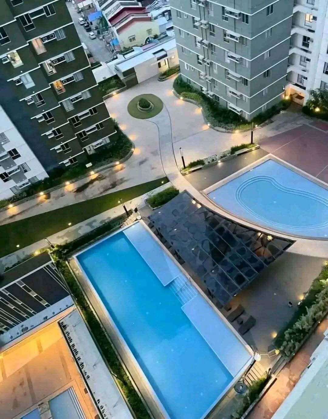A high-rise residential building with a swimming pool, a covered outdoor area, and a circular driveway.