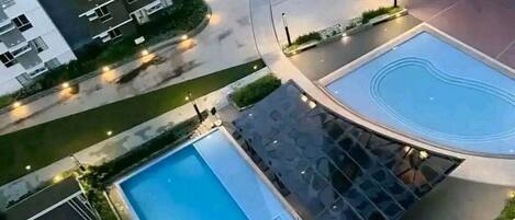 A high-rise residential building with a swimming pool, a covered outdoor area, and a circular driveway.