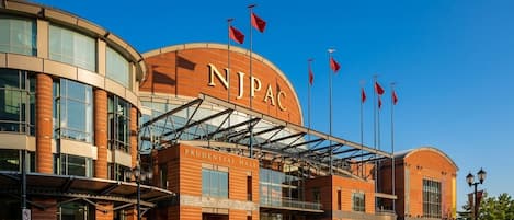A building with a curved facade, a prominent 'NJPAC' sign, and a 'PRODENTIAL HALL' label.