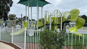 Un parque infantil con un tobogán, estructuras para escalar y una zona delimitada.