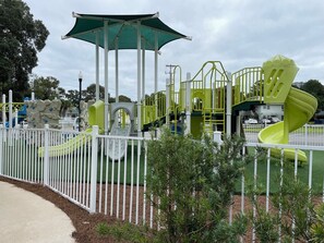 Un parque infantil con un tobogán, estructuras para escalar y una zona delimitada.