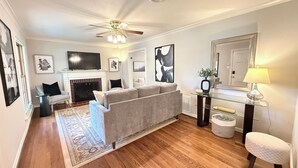 A living room with a fireplace, a sofa, a television, and a ceiling fan. - Hilltop Hideaway Near TCU, Dickies Arena & Medical District (Fort Worth)