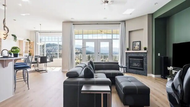 A modern living room with a sectional sofa, a flat-screen TV, and a fireplace. - Beautiful Mountain & Lake Views/Upper Level Home/King Bed/BBQ/Sleeps 5 (Kelowna)