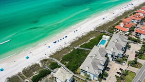 An aerial view of a coastal area with a beach, a swimming pool, and residential buildings. - Palms of Dune Allen 104 (Santa Rosa Beach)
