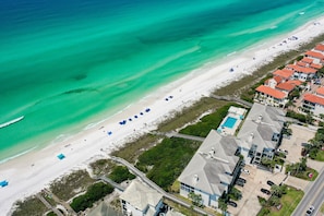 An aerial view of a coastal area with a beach, a swimming pool, and residential buildings. - Palms of Dune Allen 104 (Santa Rosa Beach)