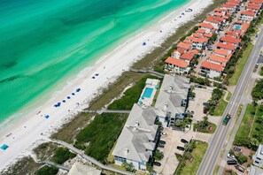 An aerial view of a coastal residential area with a beach, a swimming pool, and a road. - Palms of Dune Allen 104 (Santa Rosa Beach)