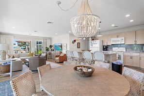 A spacious living room with a dining area, kitchen, and a large chandelier. - Palms of Dune Allen 104 (Santa Rosa Beach)
