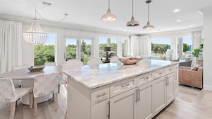 A modern kitchen with a marble countertop, white cabinetry, and pendant lighting. - Palms of Dune Allen 104 (Santa Rosa Beach)