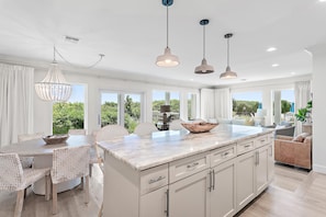 A modern kitchen with a marble countertop, white cabinetry, and pendant lighting. - Palms of Dune Allen 104 (Santa Rosa Beach)