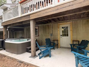 Ein überdachter Außenbereich mit Whirlpool, Holzterrasse und Sitzgelegenheit im Freien.