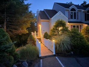 A two-story house with a wooden deck and a white railing, surrounded by greenery. - Four Seasons Retreat Hot Tub/Game Room/Ski/Swim (Lake Harmony)