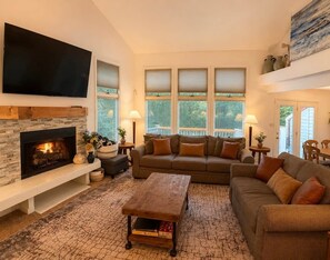 A living room with a fireplace, a large flat-screen TV, a sofa set, and a coffee table. - Four Seasons Retreat Hot Tub/Game Room/Ski/Swim (Lake Harmony)