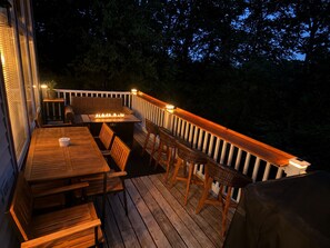Une terrasse en bois avec des meubles d’extérieur, un foyer et une rambarde.