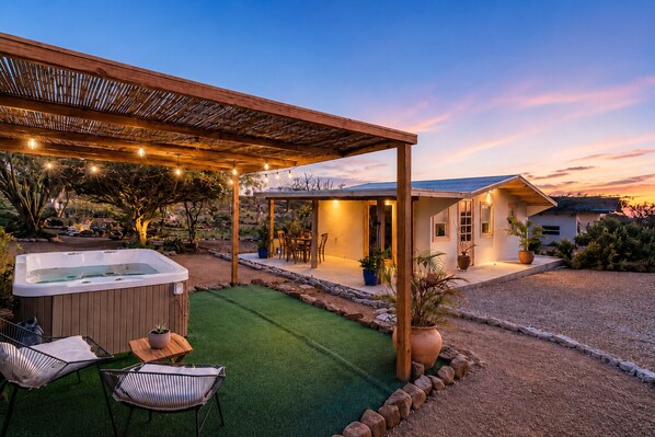 A house with a patio, a hot tub, and a covered seating area.