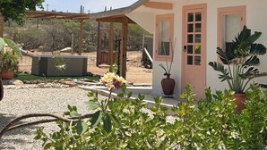 Ein Haus mit Veranda, einem kleinen Garten und blauem Himmel.