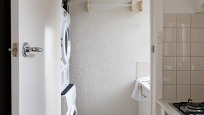 Ein kleiner Waschraum mit Waschmaschine, Wäscheständer und Waschbecken.