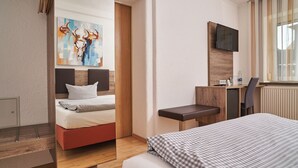 Une chambre d’hôtel avec un lit, un bureau, une télévision et un tableau au mur.