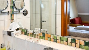Une salle de bain avec un miroir, un porte-serviettes et un pare-feu en carreaux.