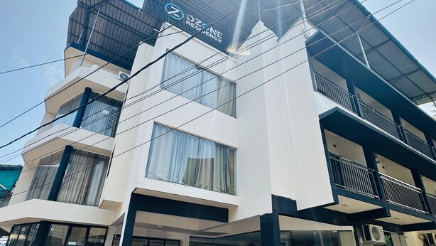 Un edificio de varios pisos con un diseño arquitectónico moderno, con balcones y ventanas amplias.
