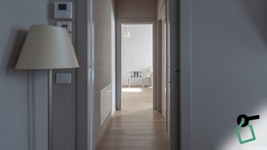 En hall med en lampa, en termostat och en dörr som leder in till ett rum.