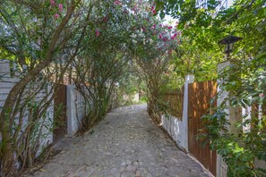 A cobblestone pathway flanked by lush greenery and a wooden gate. - Holiday Home 'El Mimbral' with Shared Pool, Wi-Fi and Air Conditioning (Vejer de la Frontera)