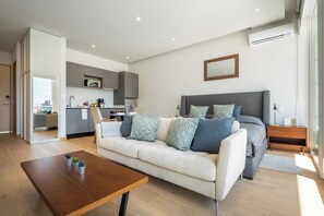 Una sala de estar moderna con sofá, mesa de centro y cama con cabecera.