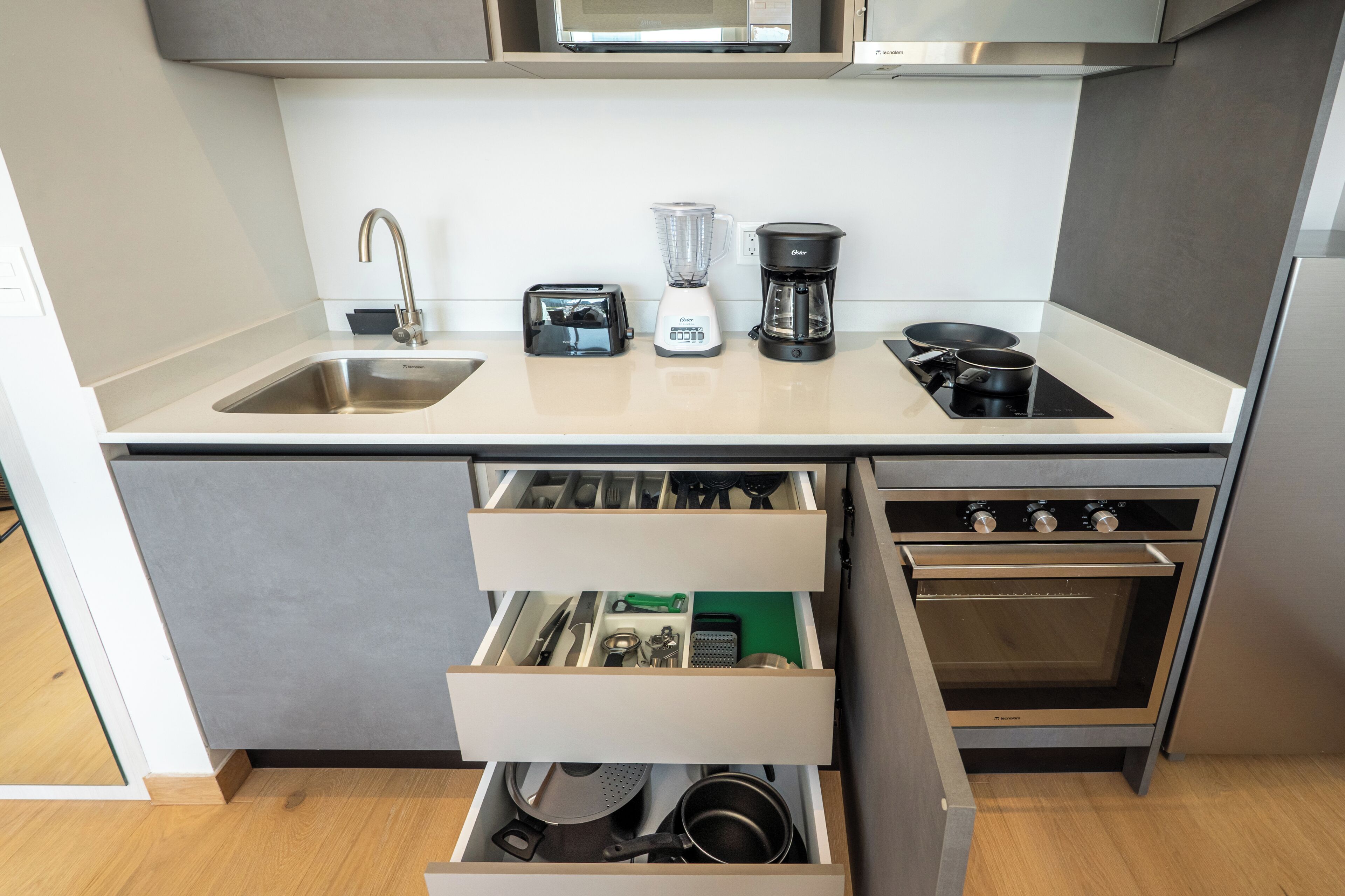 Eine moderne Küche mit Spülbecken aus Edelstahl, einem Toaster, einem Mixer, einer Kaffeemaschine und einem Einbauofen.