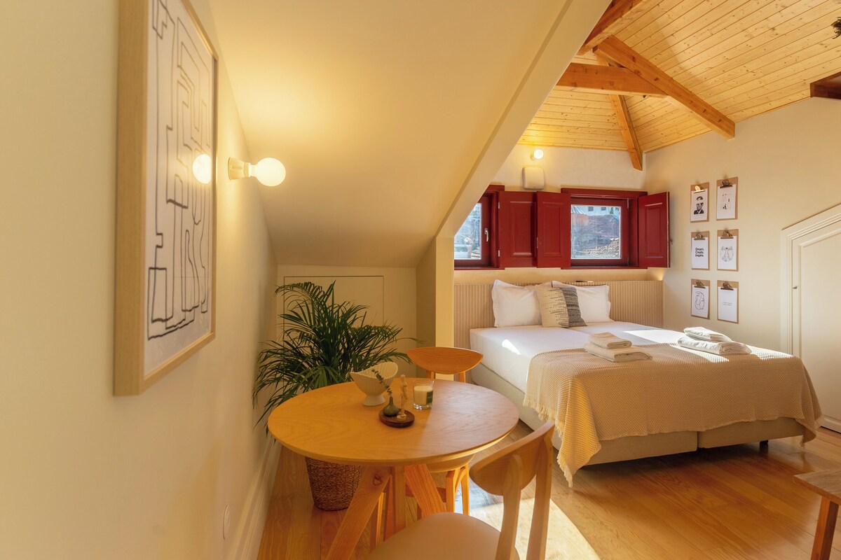 Quarto com cama, mesa de cabeceira, janela e luminária na parede.