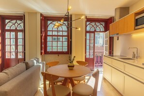 Un coin repas avec une table ronde, des chaises, un vase de fleurs et une cuisine équipée de placards et d’un téléviseur.