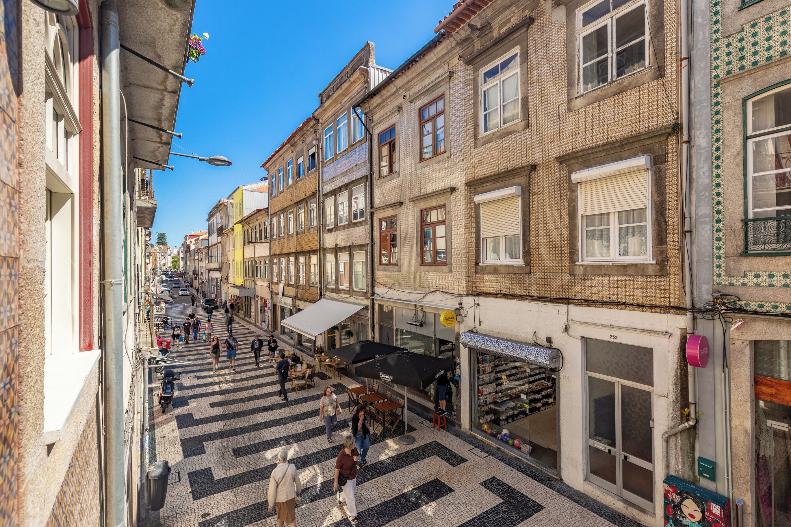 A narrow street with buildings on both sides, outdoor seating, and a pedestrian walkway.