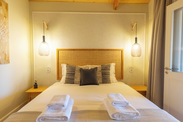 A neatly made bed with a headboard, two bedside lamps, and folded towels on the bed. - Porto Haven - Cedofeita 213 (Porto)
