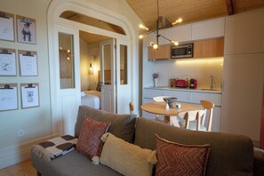 A cozy living room with a sofa, a dining table, and a kitchen area with a microwave and red kettle. - Porto Haven - Cedofeita 213 (Porto)