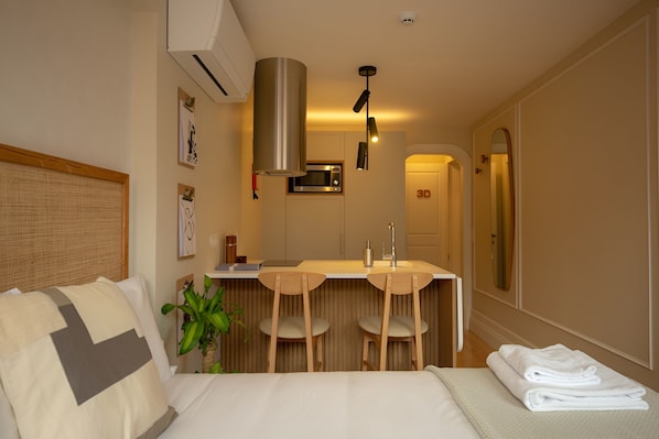 A hotel room with a bed, a desk with chairs, a microwave, and a sink. - Porto Haven - Cedofeita 213 (Porto)