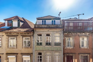 Eine Reihe von dreigeschossigen Gebäuden mit unterschiedlicher Architektur, darunter ein Balkon und ein Kran im Hintergrund.
